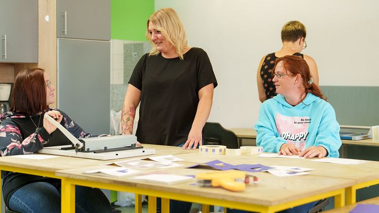 Julia Kröger (Mitte) und Klient*innen der Hephata-Werkstätten für Menschen mit Behinderungen bei der Produktion von Grußkarten. (Foto: Hephata Diakonie / Stefan Betzler)