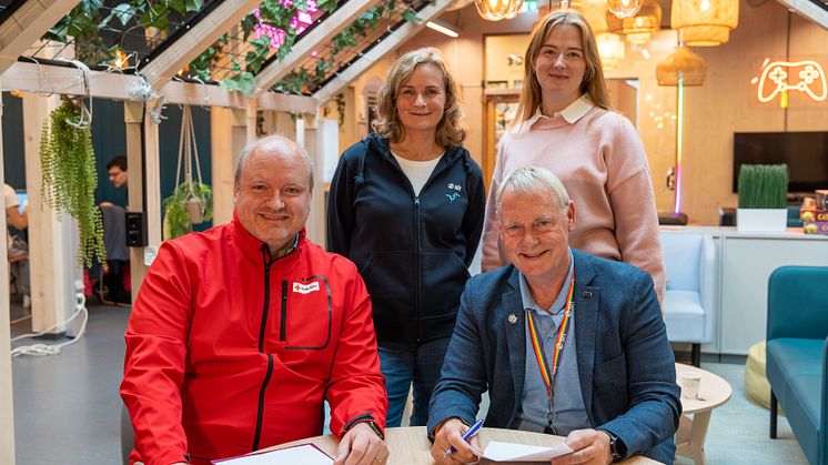 To menn og to damer signerer avtale. 