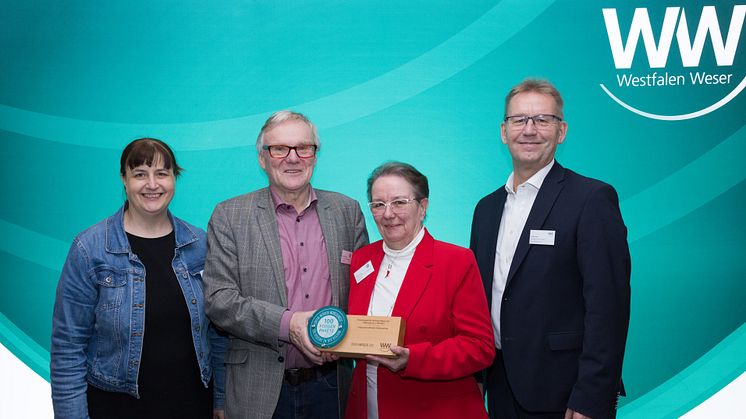 Jürgen Noch (rechts, Geschäftsführer Westfalen Weser) und Jurymitglied Stephanie Krause (links) gratulieren den Vertreter*innen des Leuchtturmprojekts der Flüchtlingshilfe Rechtes Weserufer – Hafenschule in Minden Norbert Benecke und Martina Höfel.