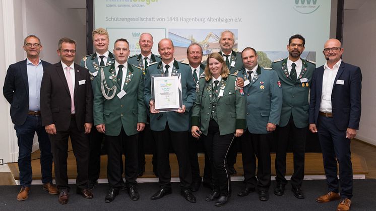 Jury-Mitglieder Heinz-Jörg Heinemann (links) und Andreas Speith (rechts) gratulieren zusammen mit dem Bürgermeister der Samtgemeinde Sachsenhagen Jörn Wedemeier (2. v. l.) der Schützengesellschaft. 