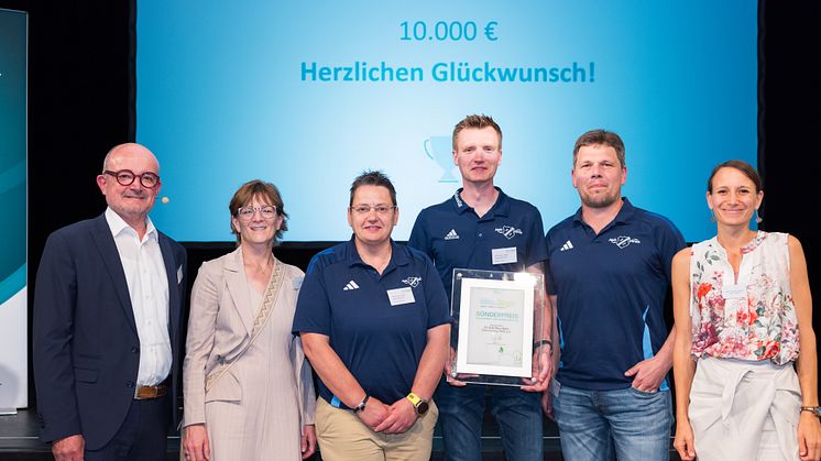 Jurymitglied Andreas Speith (l.), Bürgermeisterin von Lichtenau Ute Dülfer (2 v. l.) sowie Anja Lippmann-Krüger (rechts), Klimaschutzagentur Weserbergland mit den Mitgliedern des SV DJK „Blau-Weiß“ Kleinenberg 1932