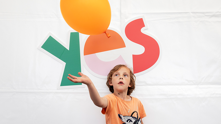 Barn som leker med en ballong. Ordet yes står stort i bakgrunden. Foto: Sofia Sabel 