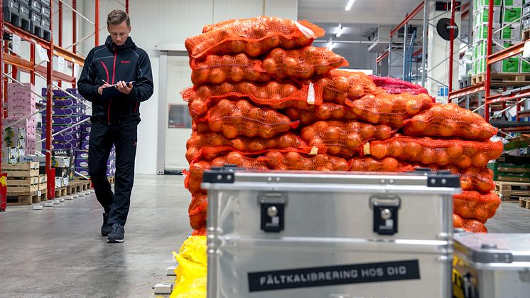 Fältkalibrerare som går i ett livsmedelslager och antecknar vid kalibrering av instrument för hög livsmedelssäkerhet