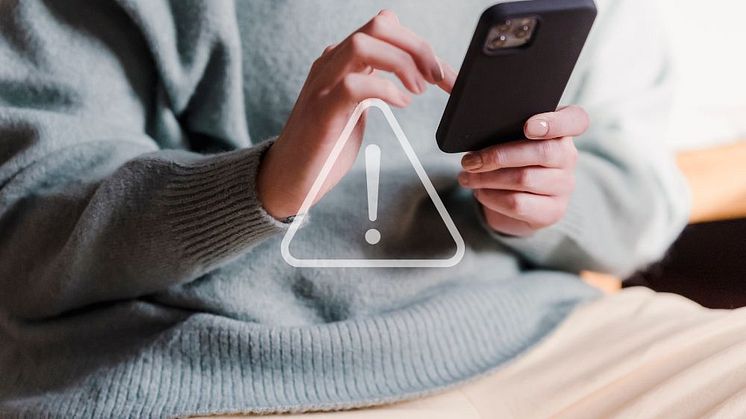 En person som håller i en mobiltelefon, artikeln handlar om misstänkta bedrägeriförsök.