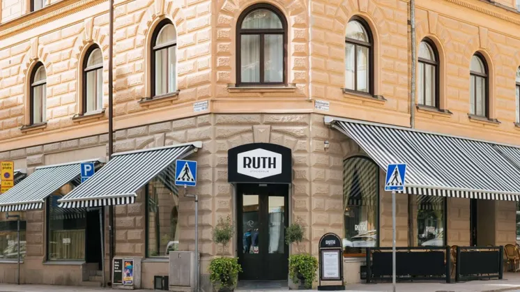 Fasaden och entrén till Hotel Ruth i Vasastan, Stockholm, med randiga markiser och Ruth-skylt ovanför entrén.