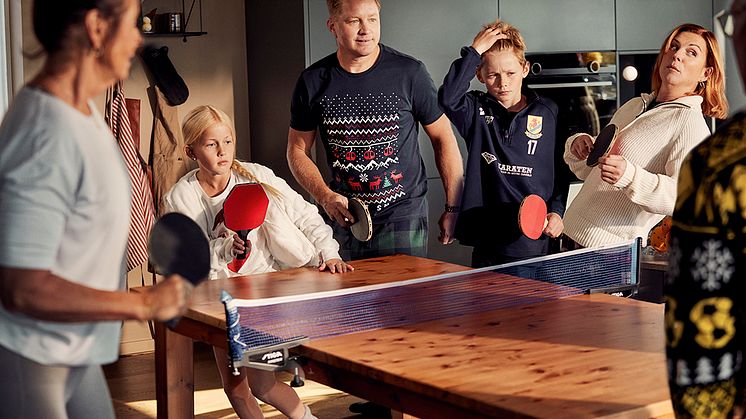 Familj som är samlade runt köksbordet och spelar pingis