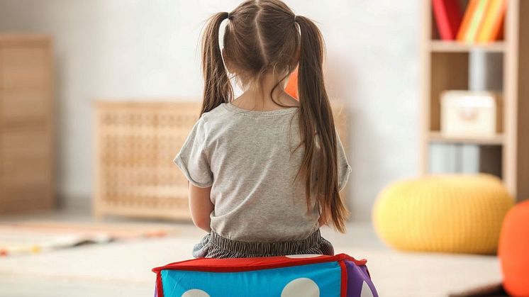 Flicka sitter ensam i ett lekrum – symboliserar autism hos flickor och deras unika sätt att uppleva världen.