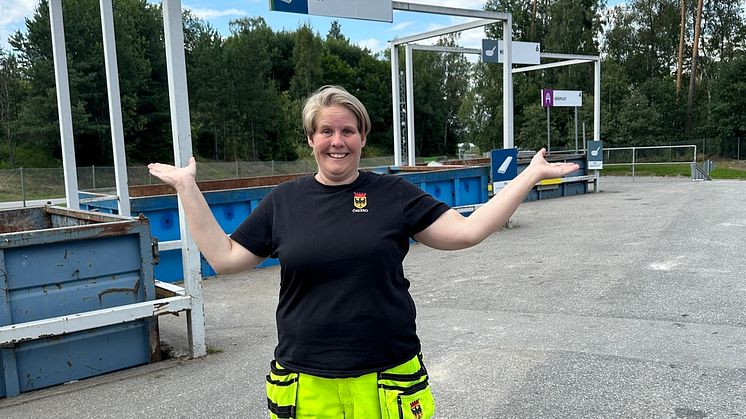 Kvinnlig anställd står framför containrar på återvinningscentral i Örebro kommun