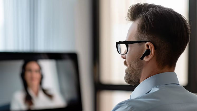 A man with glasses and headphones, seen from the side, in front of him a laptop