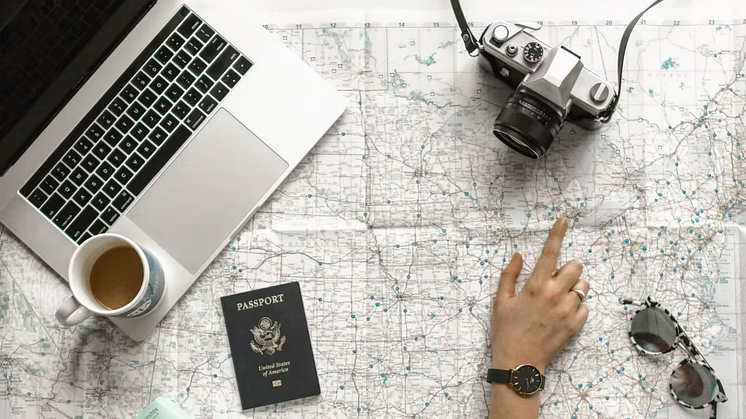 Map with laptop, camera, passfort and sunglasses on it
