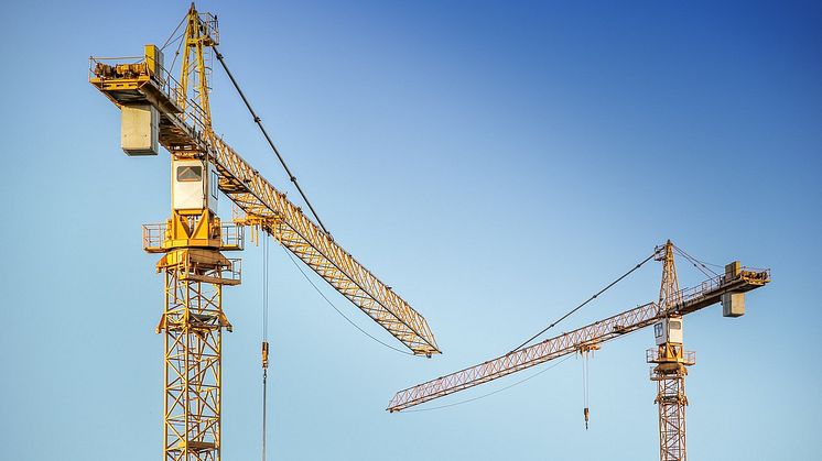 Kranar i arbete – en symbol för byggprocessens framsteg och samverkan mellan byggherre och beställare för att skapa framtidens projekt.