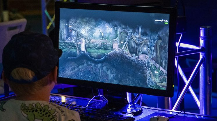 Pojke sitter vid upplyst databord och spelar dataspel