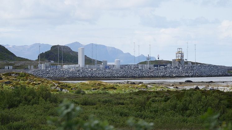 buildings situated on the coast with mountains in the background