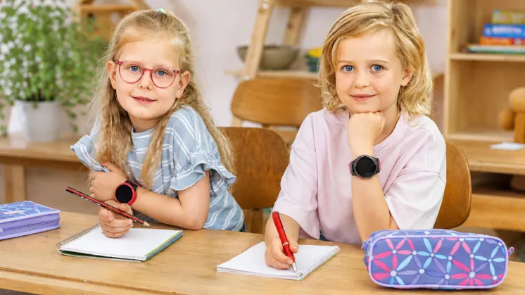 To skolebørn ved skrivebordet med Anio 6 ur på håndleddet