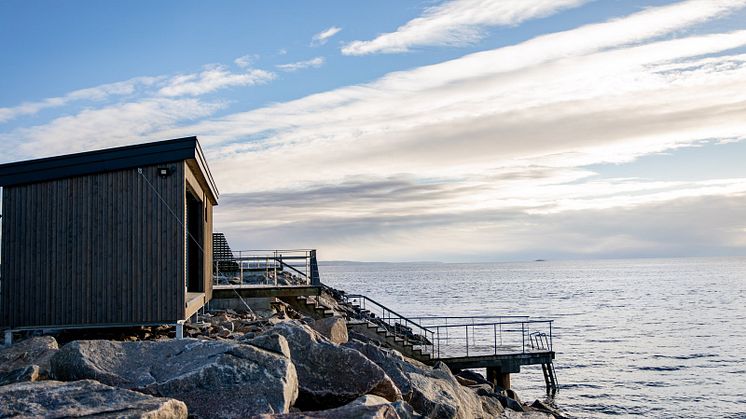 Arkitektritad bastu står på piren vid en badstege precis vid havet.