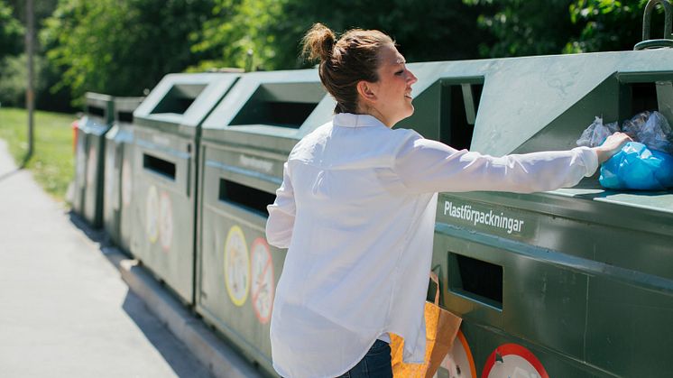 En ung kvinna sorterar plast på en återvinningsstation.