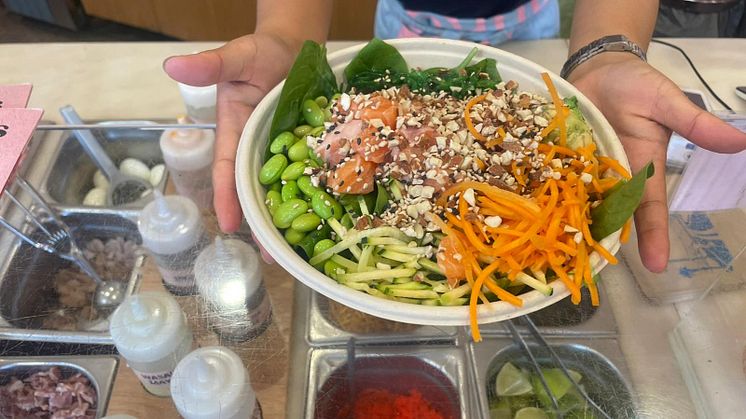 Bildet viser en som serverer pokebowl fra disken på et italiensk spisested