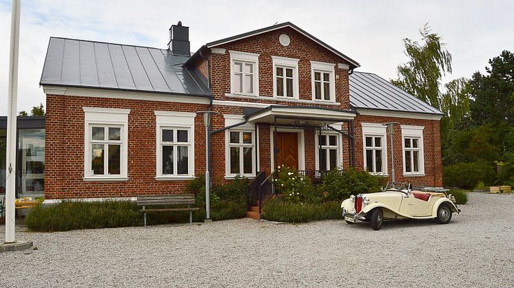 En bil parkerad framför ett rött tegelhus.
