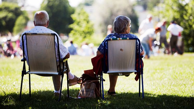 Ett äldre par som håller avstånd till anhöriga i en park.