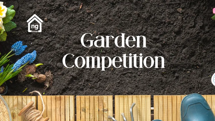 Photo of soil bordered by flowers and various gardening tools, welly boots and a straw hat
