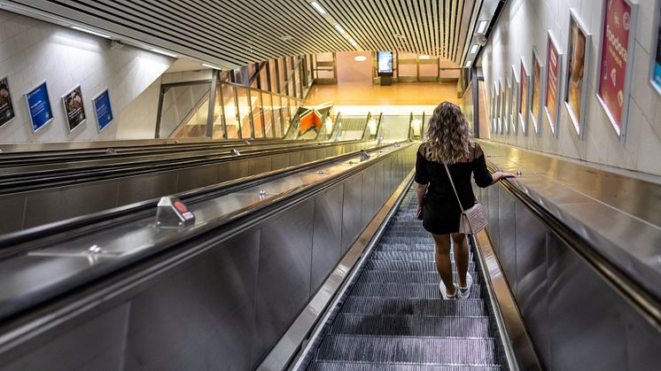 En kvinna står i en rulltrappa på en pendeltågsstation i Stockholm.