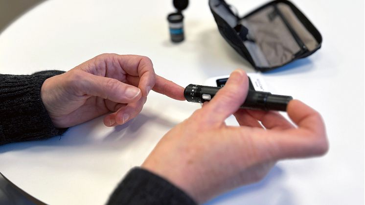 Bild på händerna på en person som mäter sitt blodsocker.