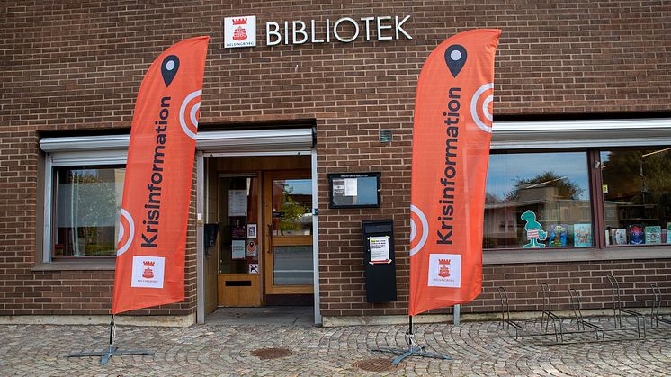 Flaggor med texten "krisinformation" utanför ett bibliotek.