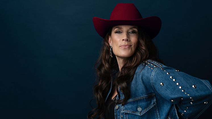 Kvinna med röd cowboy hatt och jeansjacka