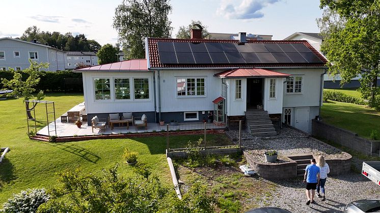 Sekelskifteshus med vita träfasader där solceller är monterade på taket. Ägarna Julia och Jonas Sjöstedt går upp mot huset. 