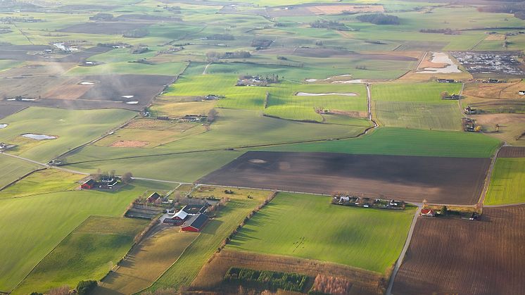 Jordbrukslandskap med fält och gårdar fotograferat av drönare,