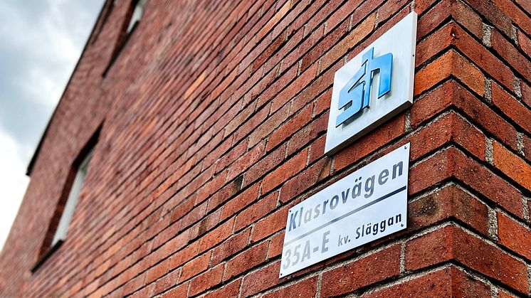 Tegelfasad på byggnad i Klasro med en gatuskylt och en Sollentunahems logotypskylt.