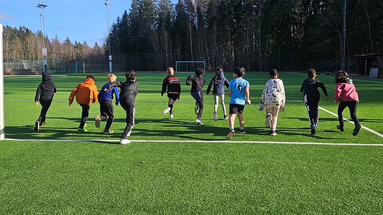 En grupp barn som springer över en fotbollsplan.