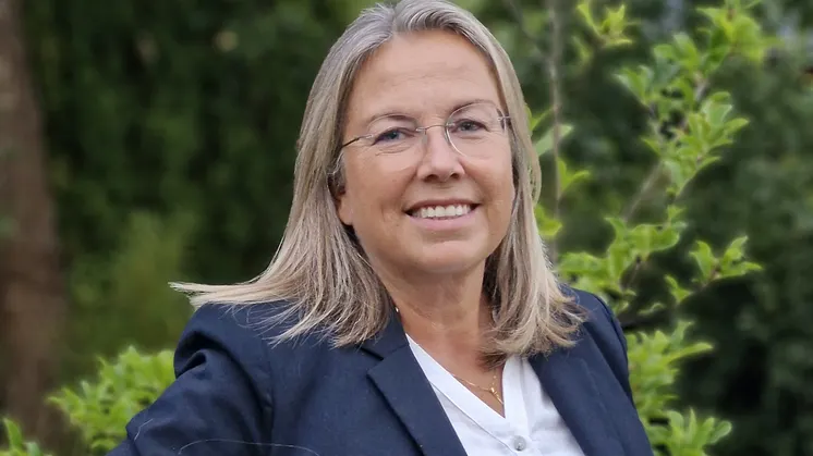 Eva Lindell, ny vd för Norrköpings Hamn, leende i blå kavaj och vit blus. Bakgrund grön växtlighet.