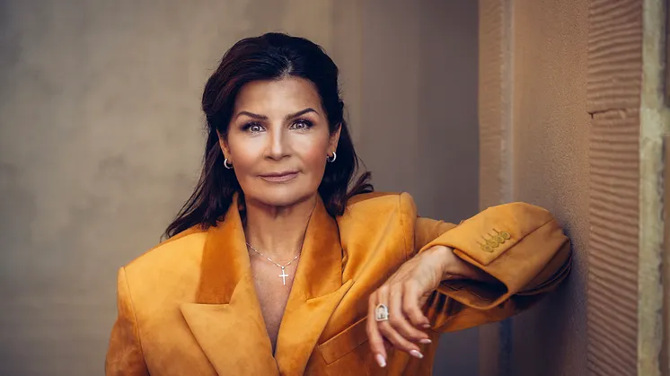 Carola Häggkvist blickar in i kameran iklädd en brandgul kavaj