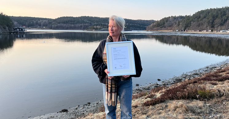 Vid strandkanten utanför Strömstad håller Ann-Sofie upp certifikatet och blickar ut över havet, symboliserande en ljus framtid för etisk AI-användning. SamCert som verkar i Sverige och Norge, har blivit det första AI-certifierade företaget i Europa.