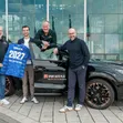Schalke 04 und Sport Auto Plus zeigen vor einem Auto ein Trikot mit der Jahreszahl zur Verlängerung