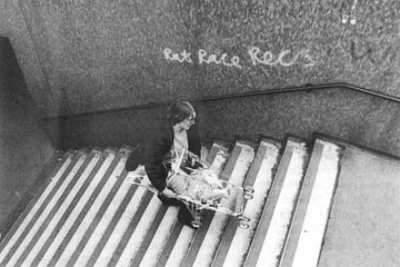 Matrix medgrundare Anne Thorne bär en barnvagn uppför trappan till en tunnelbana i Aldgate, östra London från "Urban Obstacle Courses" i Making Space: Women and the Man-Made Environment (Pluto Press, 1984). Foto: Liz Millen.