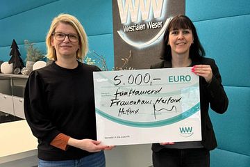 Nadine Heinen (links), Traumapädagogin beim Frauenhaus Herford, nimmt die Spende von Christiane Rüsel (rechts), Kommunalreferentin bei Westfalen Weser, entgegen.