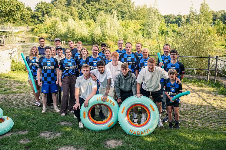 Auf dem Foto sind 25 Personen zu sehen, die in die Kamera lächeln. Die Menschen in der ersten Reihe halten Schwimmreifen.