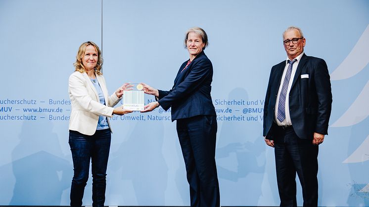 Universitätspräsidentin Prof.in Dr.in Verena Pietzner (m.) nimmt die Auszeichnung von Bundesumweltministerin Steffi Lemke entgegen. Rechts: Ulrich Feuersinger, Sprecher der Initiative Pro Recyclingpapier. Foto: Christoph Wehrer / BMUV