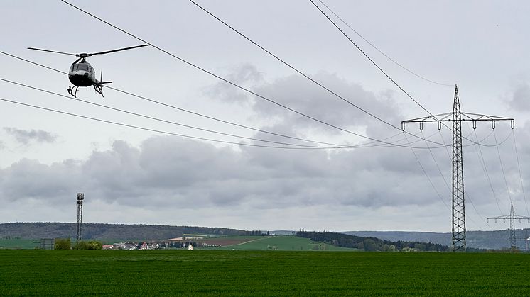 Aus dem Hubschrauber werfen Techniker der Bayernwerk Netz GmbH einen genauen Blick auf die Hochspannungsleitungen. So erkennen sie, ob Wartungsarbeiten oder Reparaturen notwendig sind.