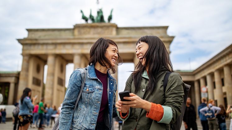 Berlin_Zwei_Frauen_stehen_lachend_vor_dem_Brandenburger_Tor