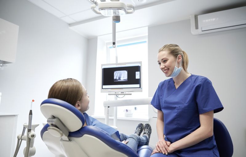 Leende tandvårdspersonal med ung patient på klinik.