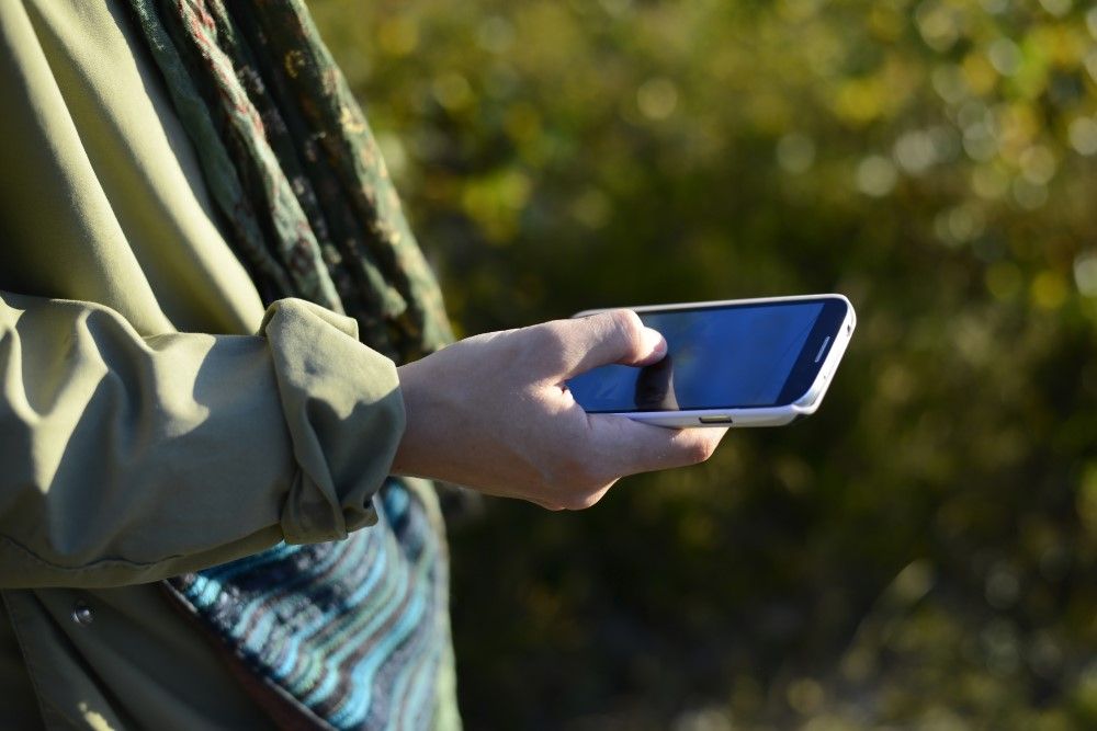 Närbild på person som håller i en telefon.