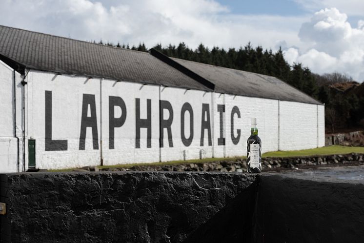 Laphroaig36YearOldWallCollection_BottleInFrontOfDistillery.jpg