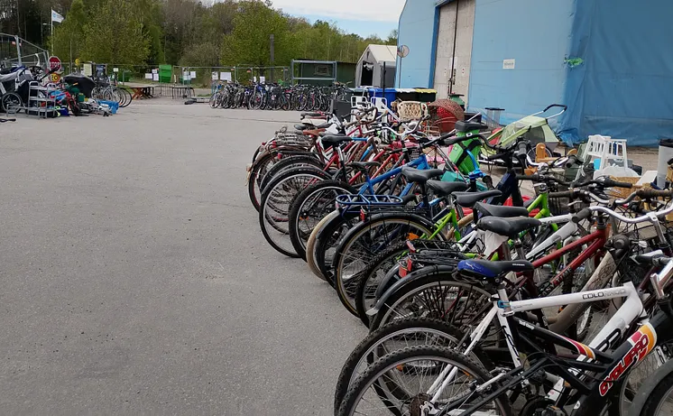 En lång rad begagnade cyklar står parkerade utanför ett stort blått tält vid Vika återvinningscentral.