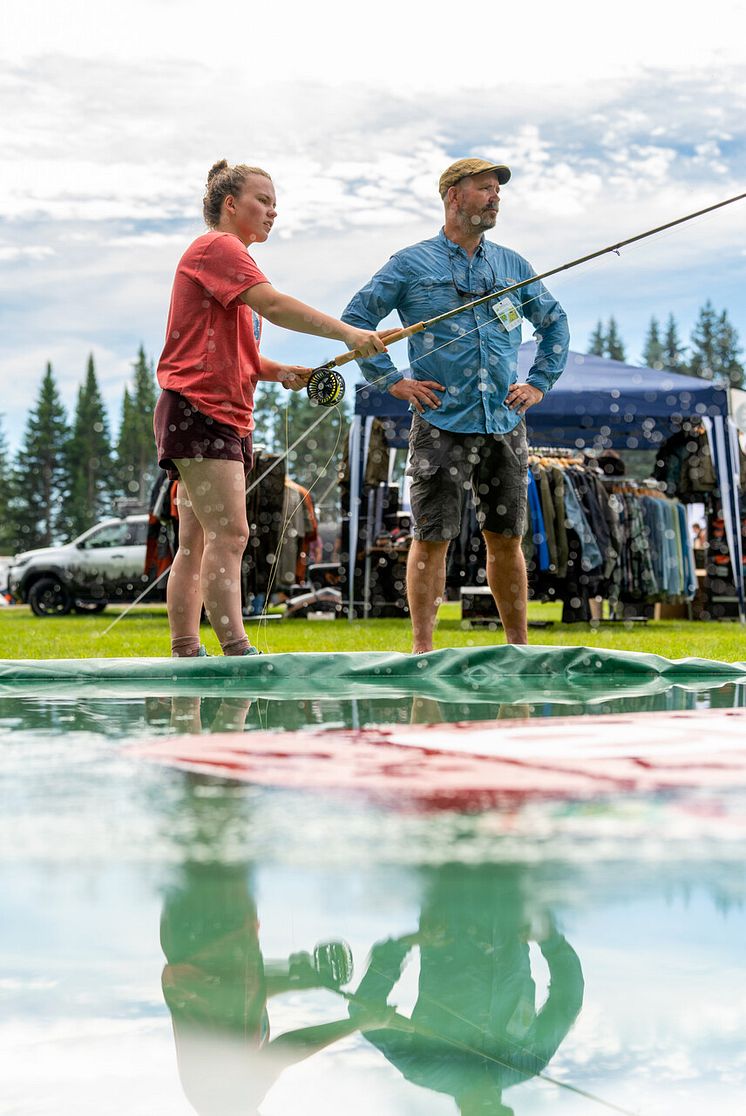En kvinne som kaster med fluestang og en mann som står og ser på.