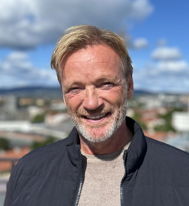 Bilde av Rune Storm, en mann i mørk jakke med bylandskap i uskarp bakgrunn. 