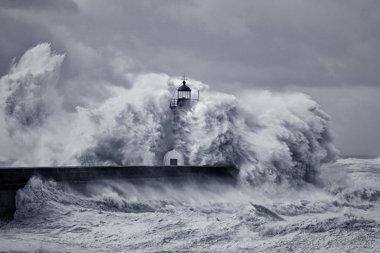 Stock massive wave hitting a lighthouse on a pier