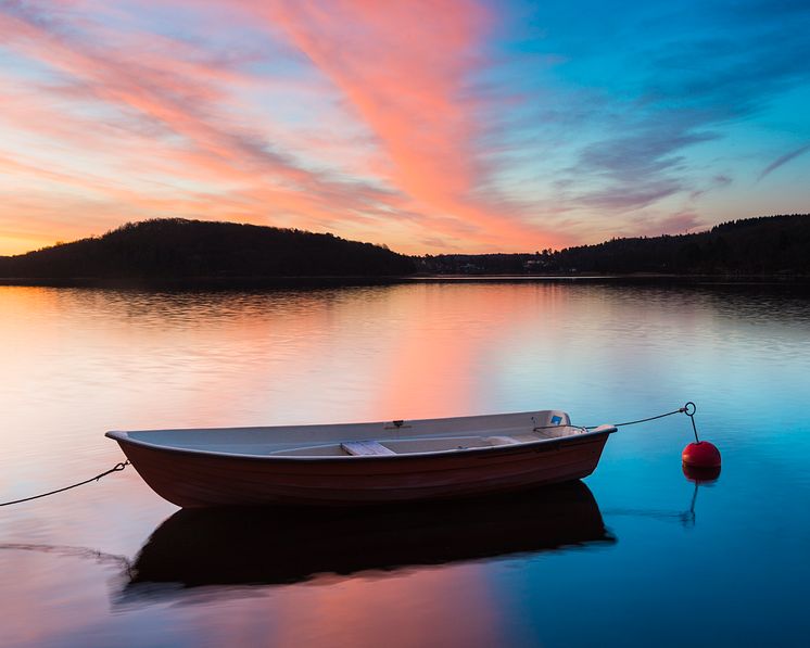 43482044-reflection-of-moored-boat-on-lake-with-dramatic-sky